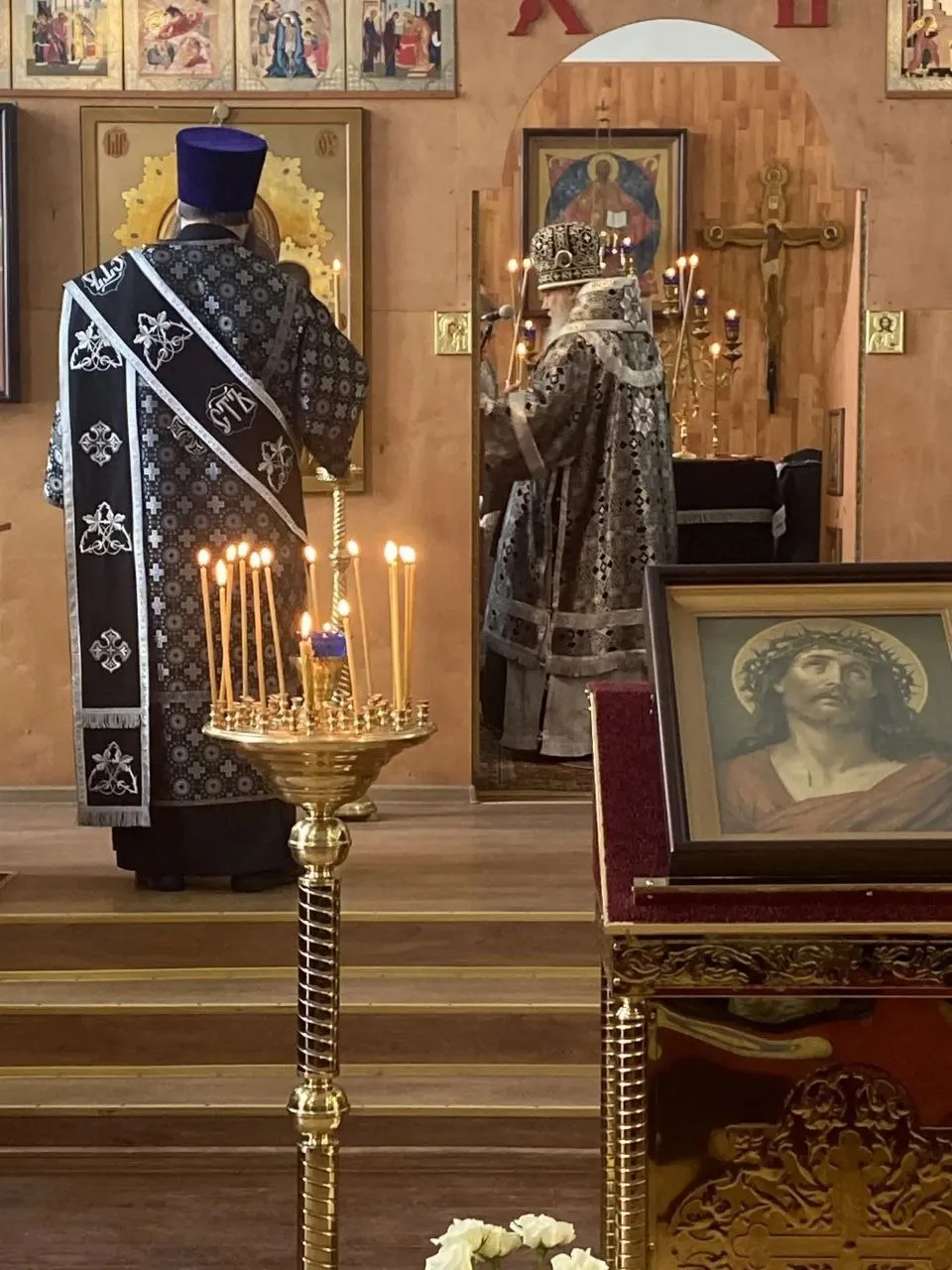 Икона Христа в терновом венце на аналое, за ней священнослужители за литургией