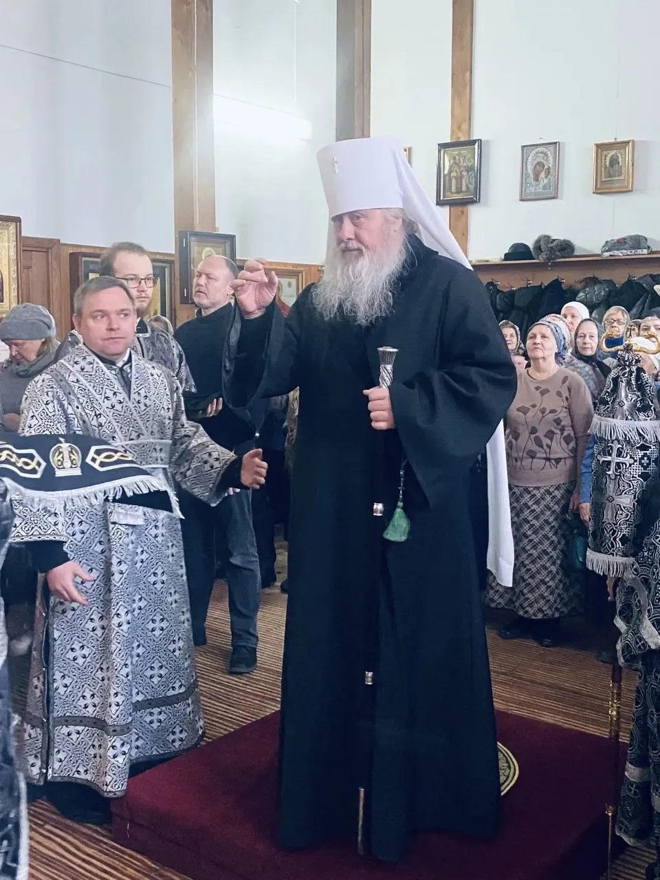 Архиерей в чёрной мантии и белом клобуке обращается к прихожанам