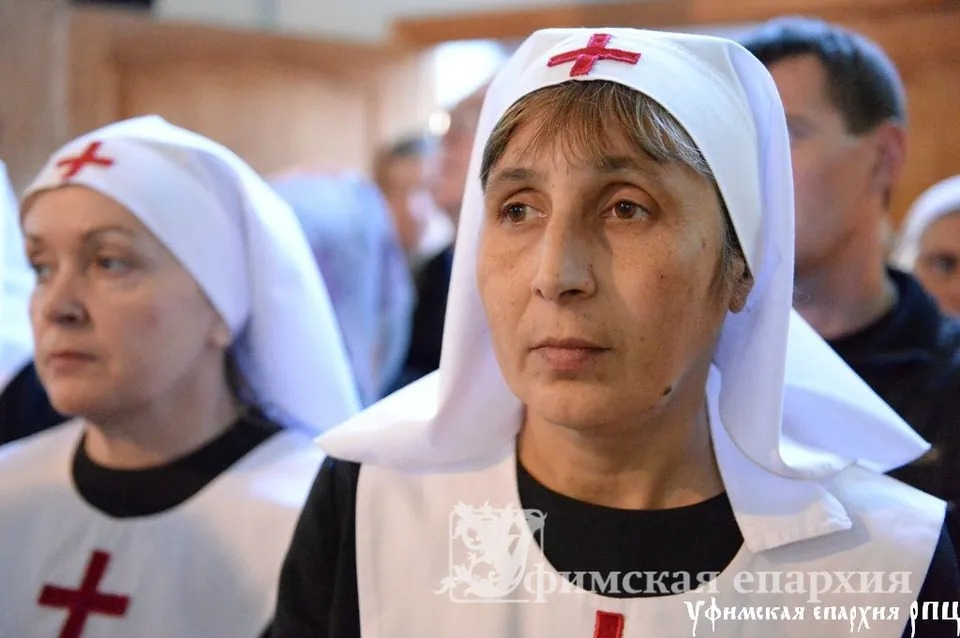 Крупным планом две сестры милосердия в белых косынках с красным крестом на груди